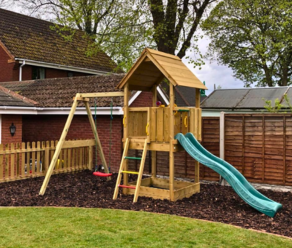 Wooden garden climbing frame with slide and swing in a backyard